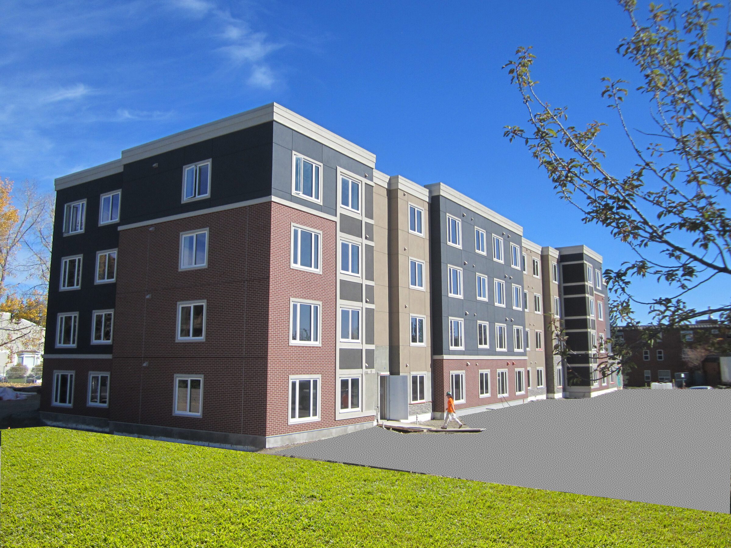 A modern four-story apartment building with red brick and dark grey exterior walls. ICF reduces seniors' monthly utility bills.